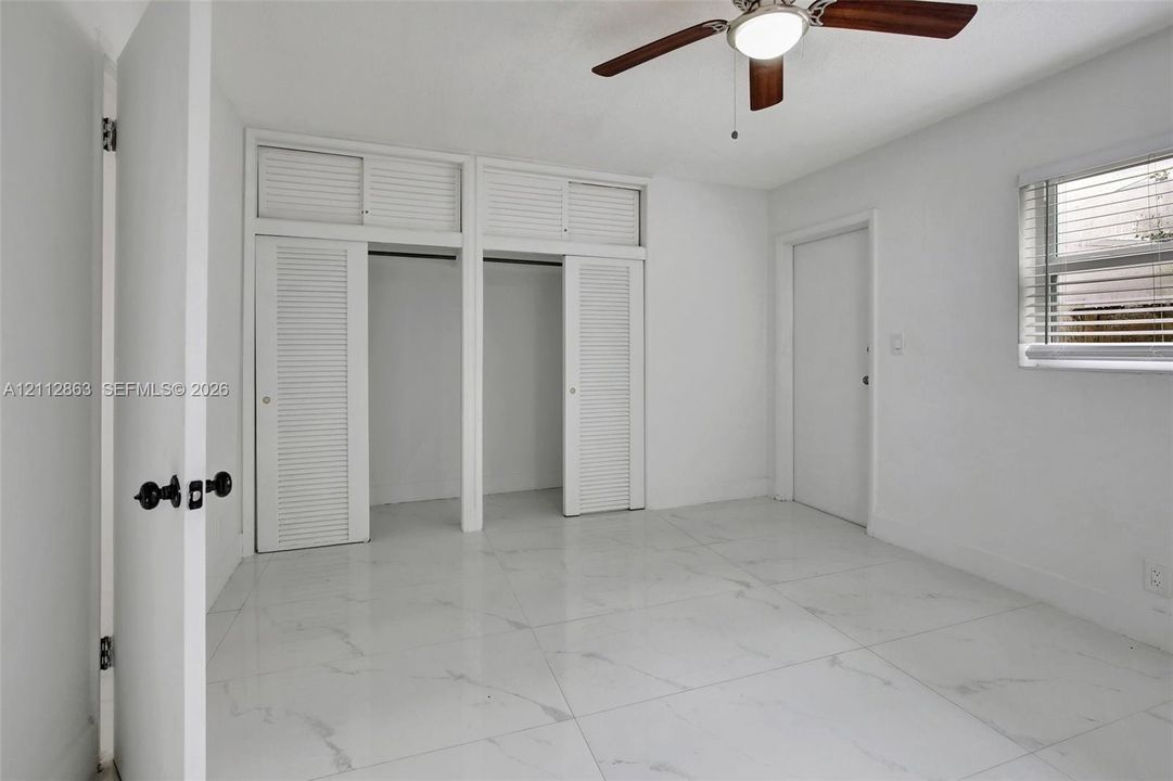 Large-format tile flooring, dual closets with overhead storage, and ceiling fan with integrated lighting