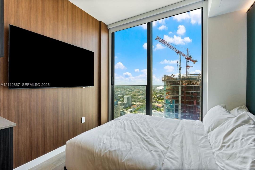 Floor-to-ceiling windows, wood-finish accent wall, and light-toned flooring