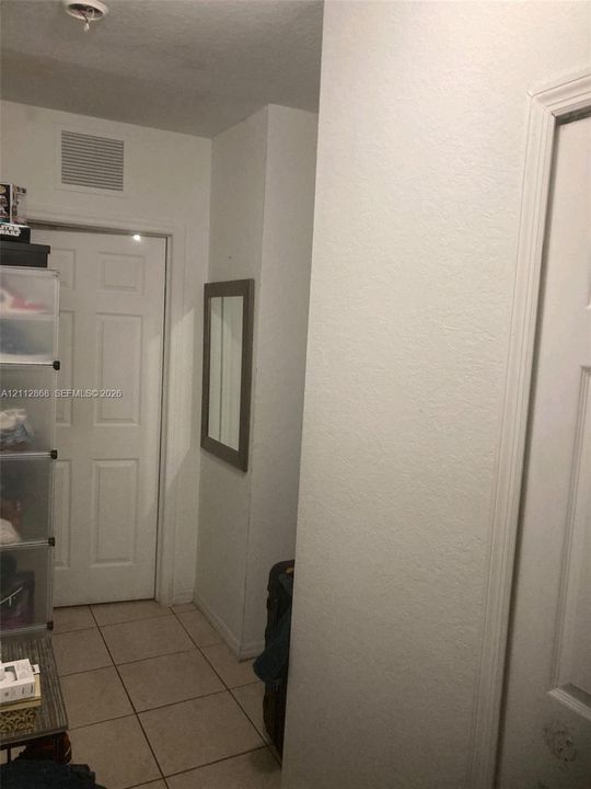 Neutral-toned tile flooring, six-panel interior doors, and wall-mounted mirror