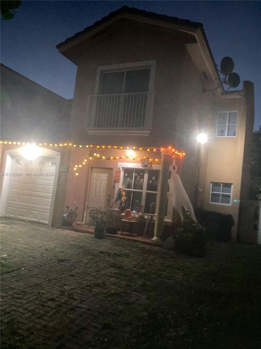 Two-story exterior featuring a paved driveway, integrated garage, covered front entryway with a decorative column, and an upper-level balcony