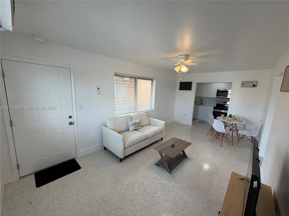 Living area featuring terrazzo flooring, white walls, and a ceiling-mounted light fixture with fan