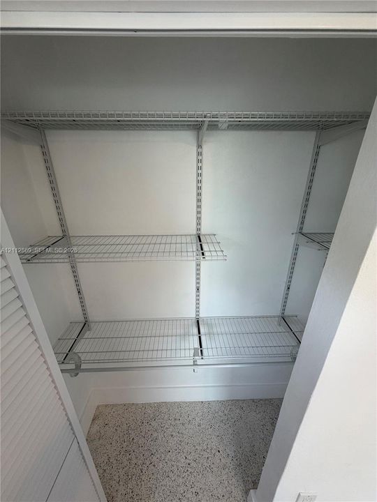 Closet interior featuring multi-tier wire shelving, adjustable wall-mounted support tracks, and speckled composite flooring
