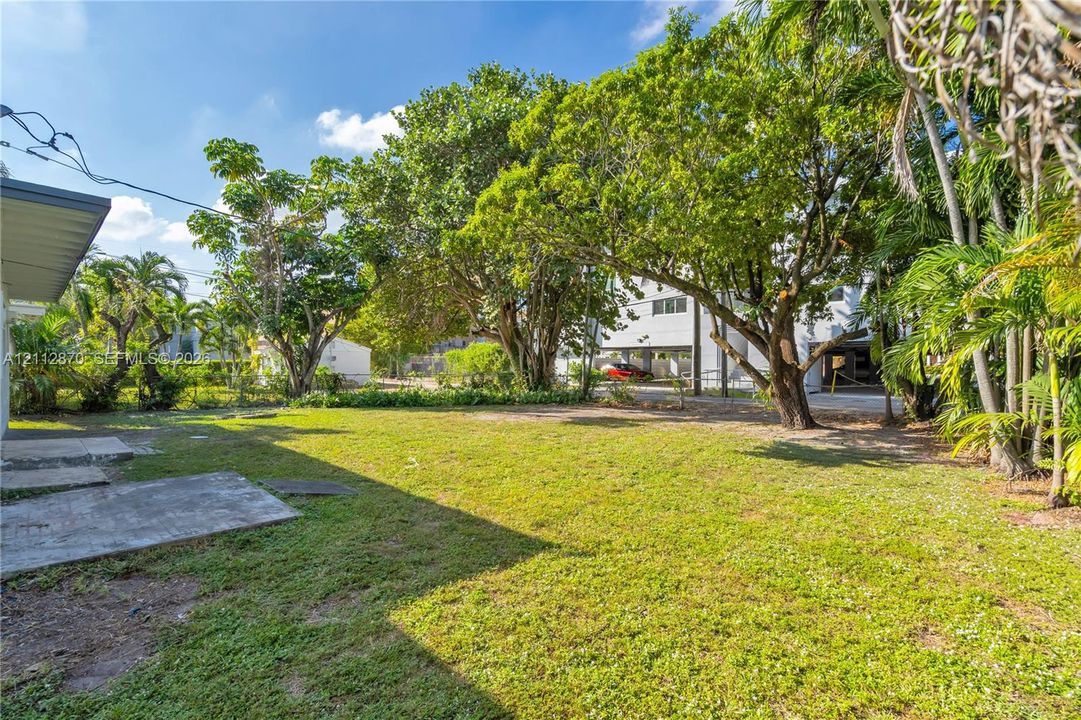 Expansive backyard featuring a concrete patio, established trees, and mature landscaping