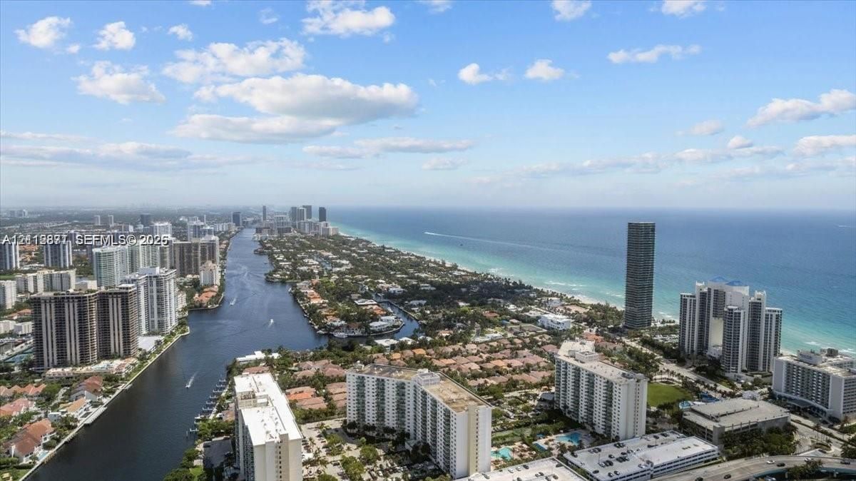 Aerial perspective showcasing the coastline, expansive ocean horizon, residential waterway, and urban skyline