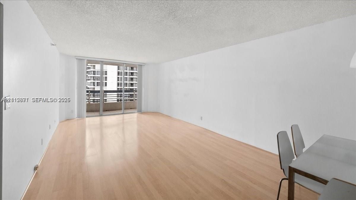 Open-concept interior featuring light wood-finish flooring and sliding glass balcony doors