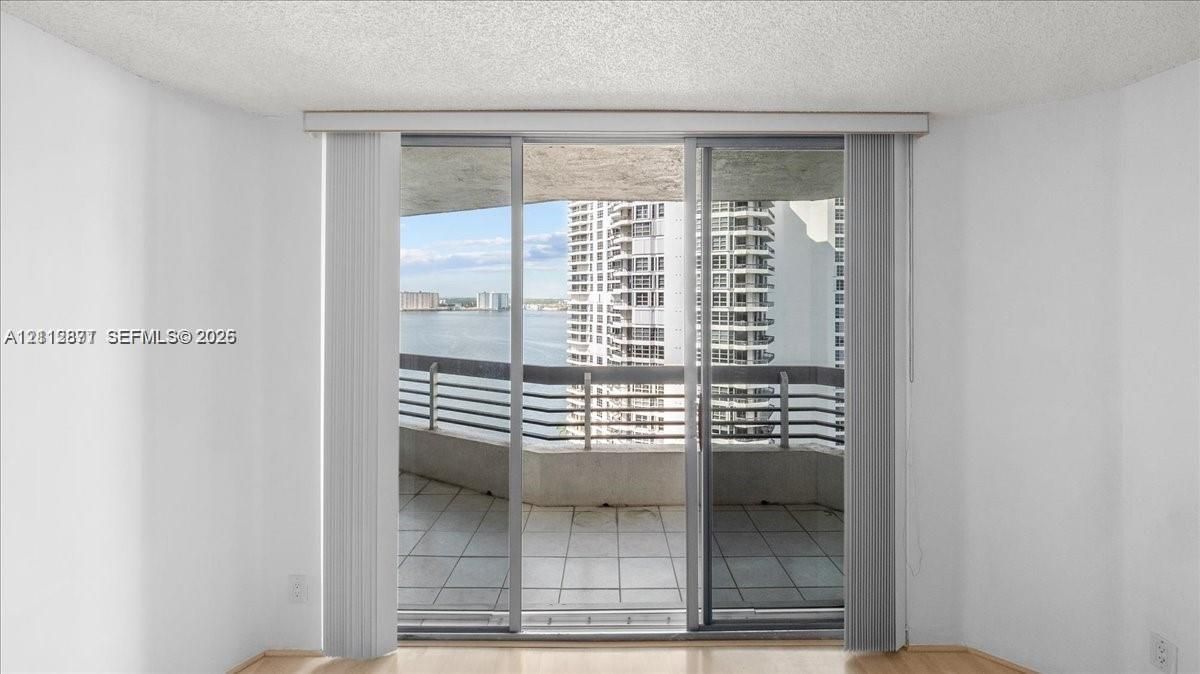 Sliding glass doors opening to a tiled balcony with a metal railing and water scenery