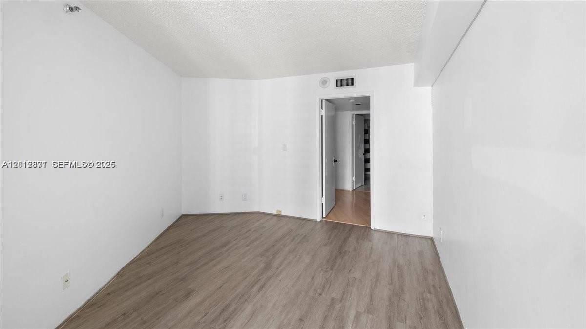 Interior space featuring neutral wall paint, wood-finish flooring, and a textured ceiling