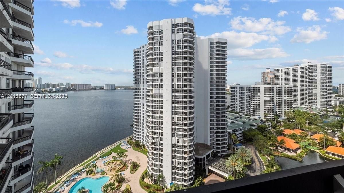 High-rise residential tower featuring private balconies, waterfront location, swimming pool, and landscaped grounds