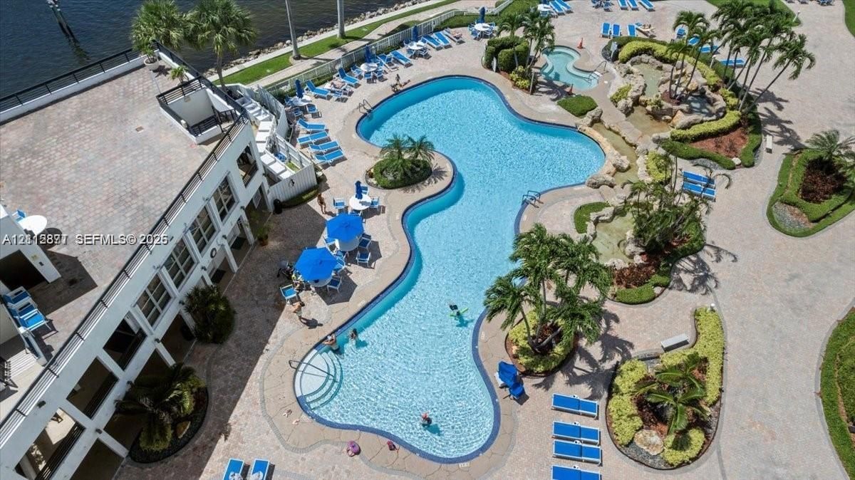 Community amenities featuring a large resort-style swimming pool, spa, paver patio, professional landscaping, and deep-water access