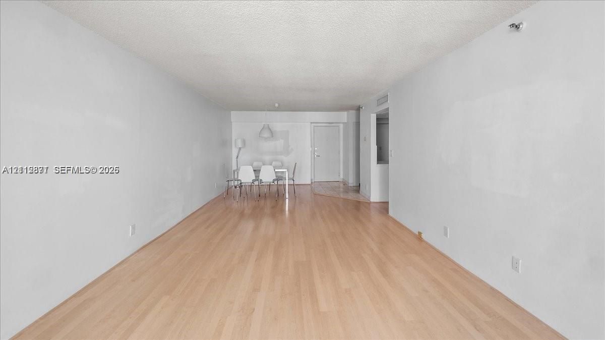 Open-concept interior featuring light-tone wood-finish flooring, a neutral color palette, and an integrated pendant light fixture