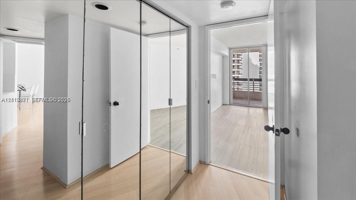Interior hallway featuring floor-to-ceiling mirrored sliding closet doors, wood-finish flooring, and recessed lighting