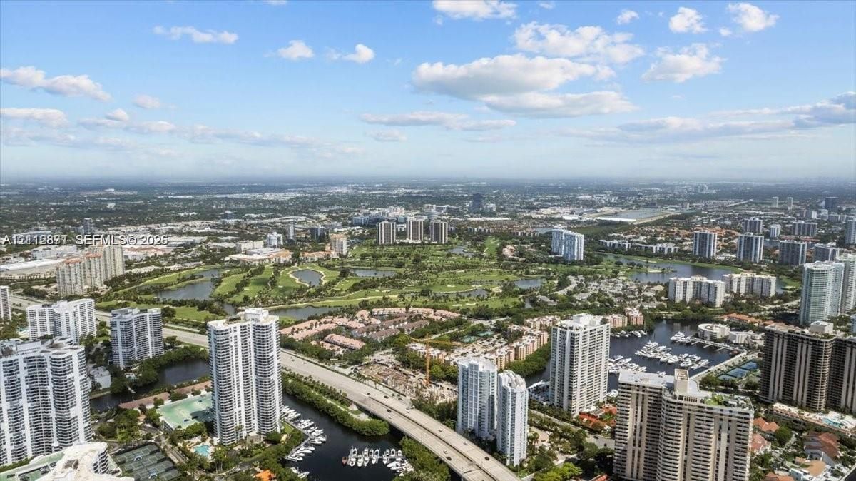 Aerial perspective showcasing expansive water features, golf course fairways, multi-level residential structures, and marina slips