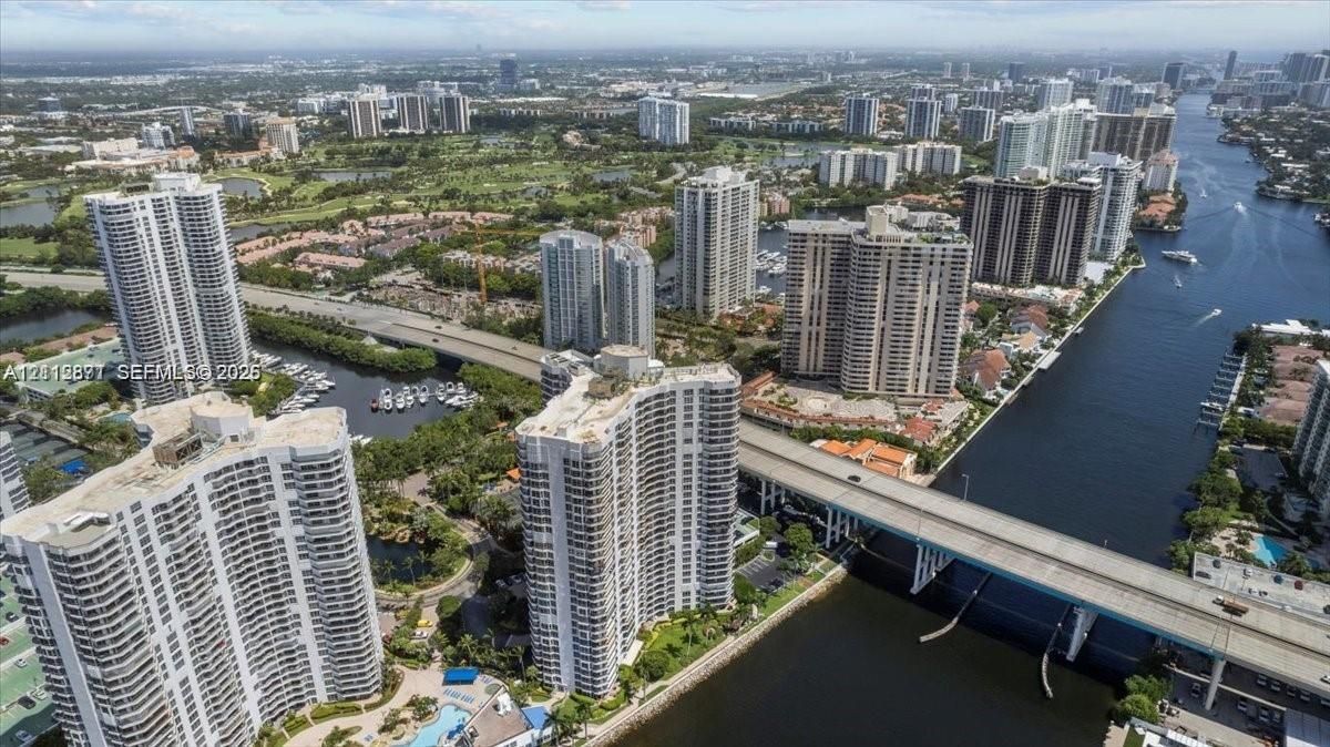 Aerial perspective of high-rise towers featuring water-front positioning, integrated outdoor swimming pool, and proximity to inland waterways