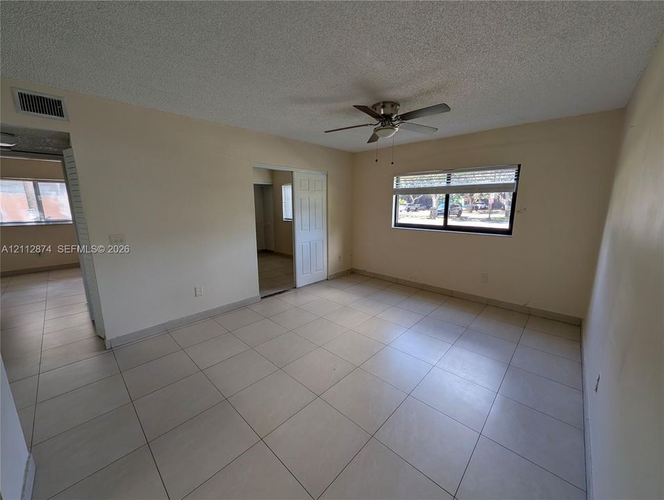 Interior space featuring large-format tile flooring, a centered ceiling fan with integrated lighting, and a horizontal sliding window with horizontal blinds