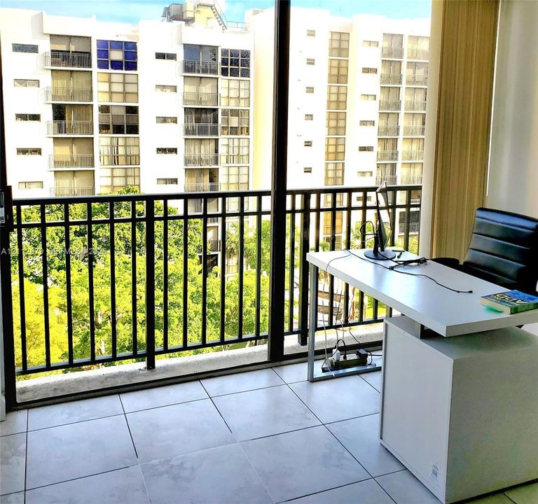 Floor-to-ceiling glass sliding doors opening to a private balcony with black metal railing and large-format ceramic tile flooring
