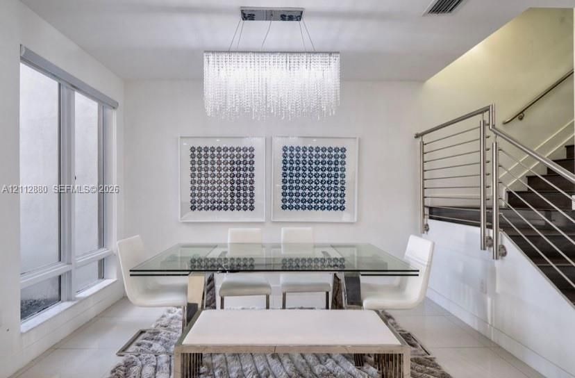Rectangular crystal chandelier, large-format tile flooring, and a stainless steel horizontal cable railing system