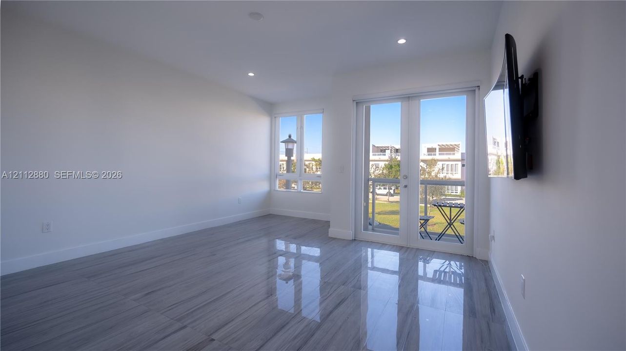 Master Bedroomflooring, recessed lighting, multi-pane windows, and a glass-paned door opening to an exterior balcony with a metal railing