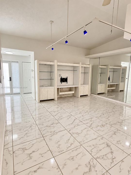 Large-format stone-patterned tile flooring, built-in floor-to-ceiling cabinetry with glass shelving, expansive wall-to-wall mirrors, and adjustable track lighting