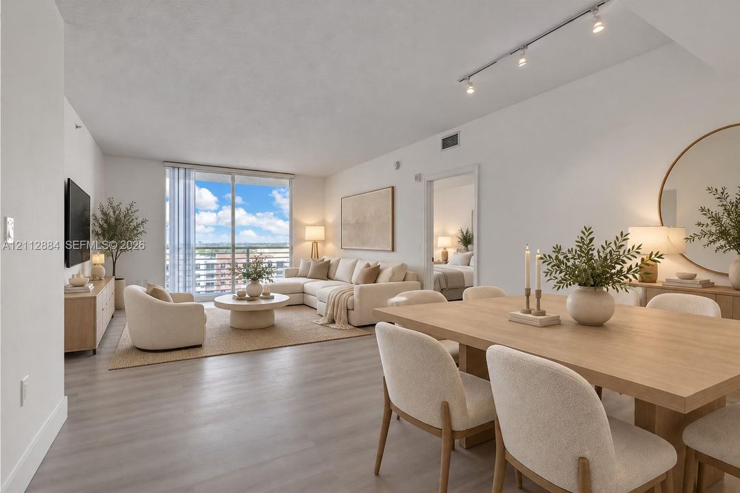 Open-concept living space featuring wood-finish flooring, sliding glass balcony doors, and adjustable track lighting