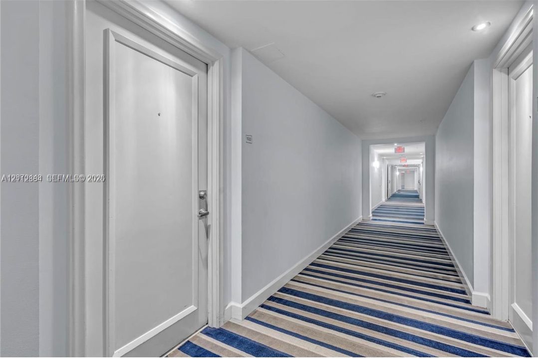 Interior hallway featuring recessed ceiling lighting, multi-toned striped carpeting, and white paneled doors