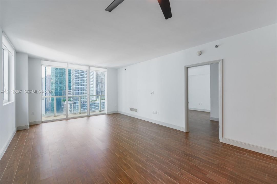 Living space featuring floor-to-ceiling windows, wood-finish flooring, and a ceiling-mounted fan