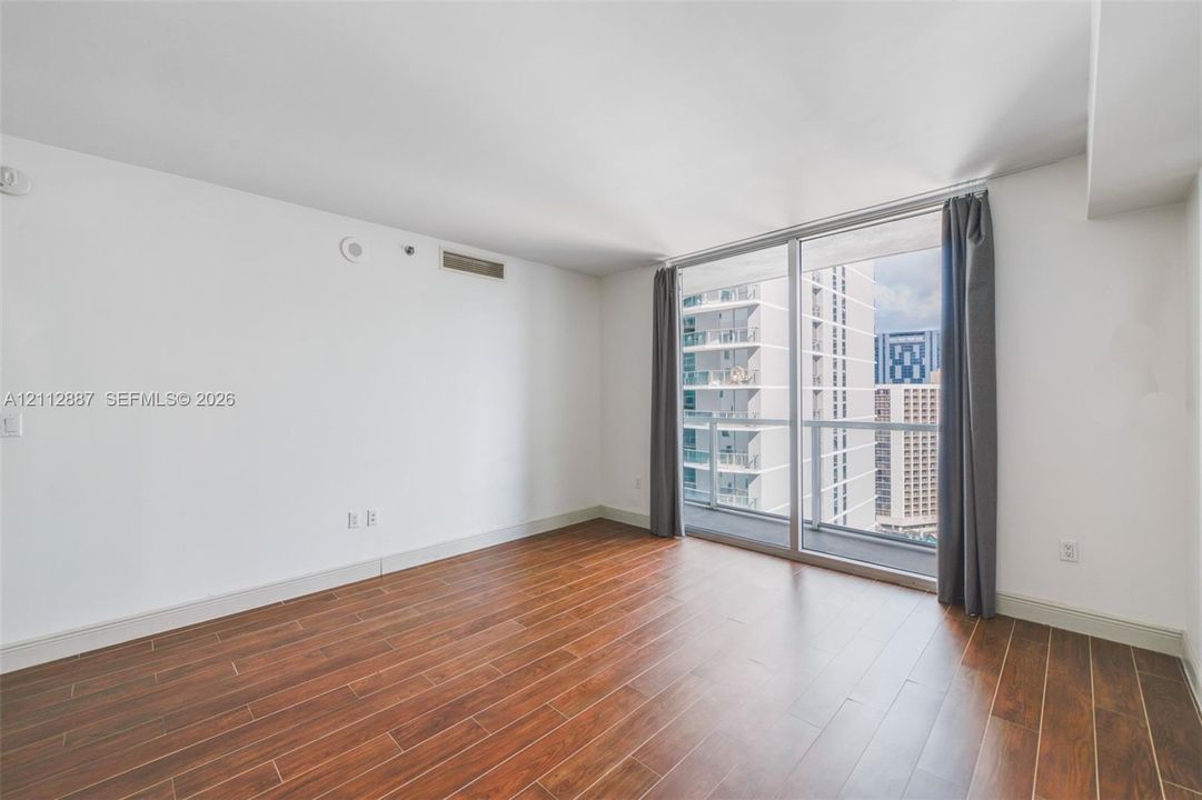 Interior space featuring wood-finish flooring, floor-to-ceiling glass sliding doors, and access to an exterior balcony