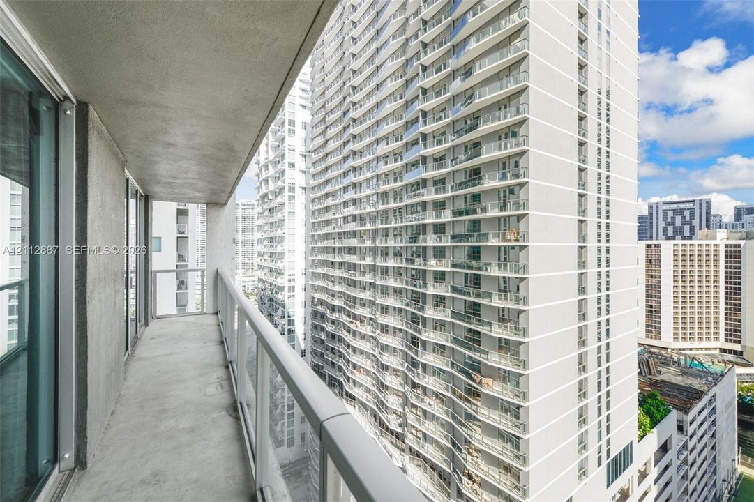 Private balcony featuring a concrete floor, glass and metal railings, and floor-to-ceiling glass sliding door access