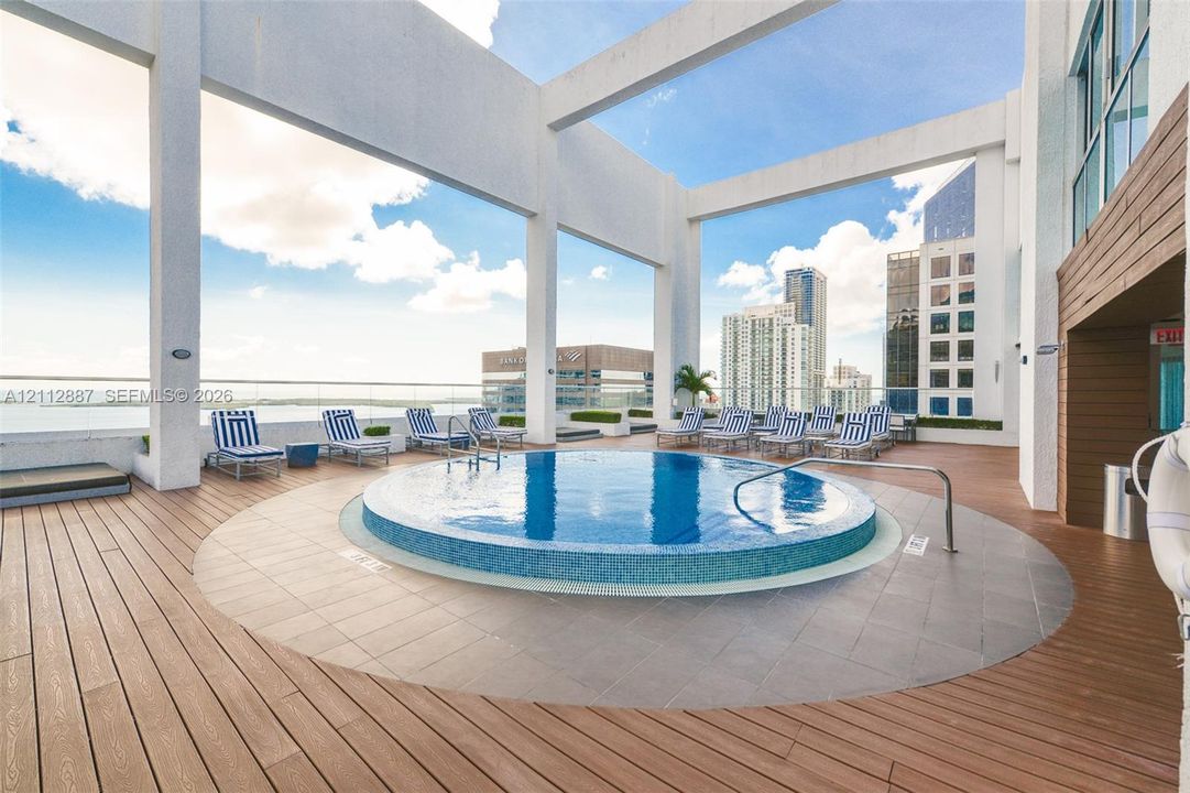 Rooftop terrace featuring a circular tile-finish pool, glass panel railing, wood-finish decking, and a structural concrete frame