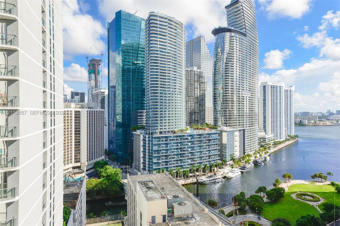 High-rise urban architecture featuring glass-facade towers, private recessed balconies, and expansive water frontage overlooking a river and landscaped green space
