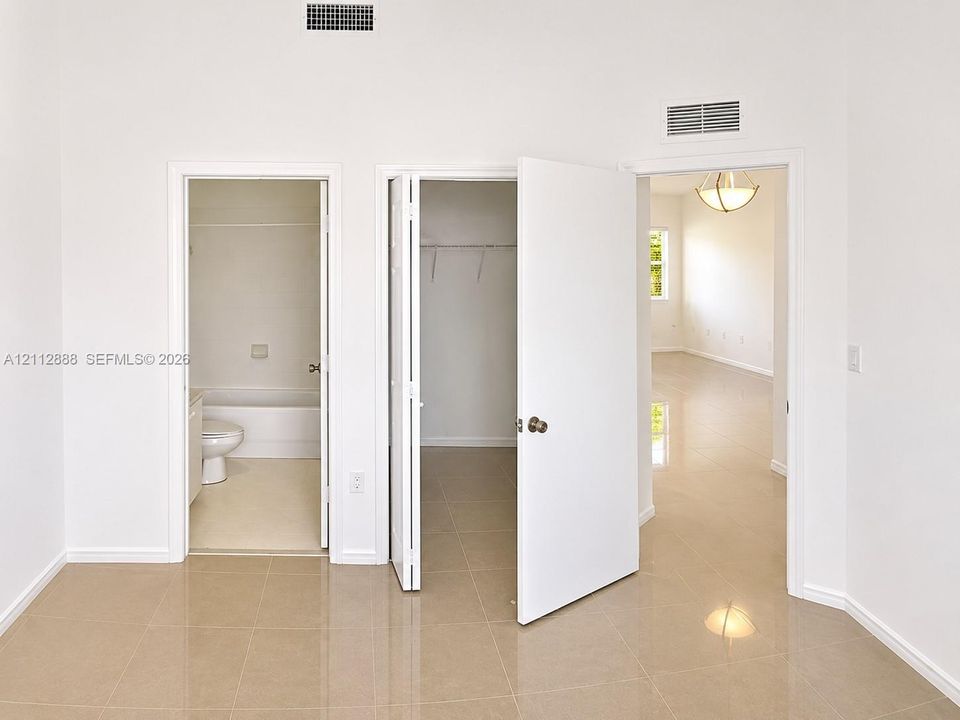 Neutral-toned tile flooring, recessed interior doors, and a walk-in closet with built-in shelving