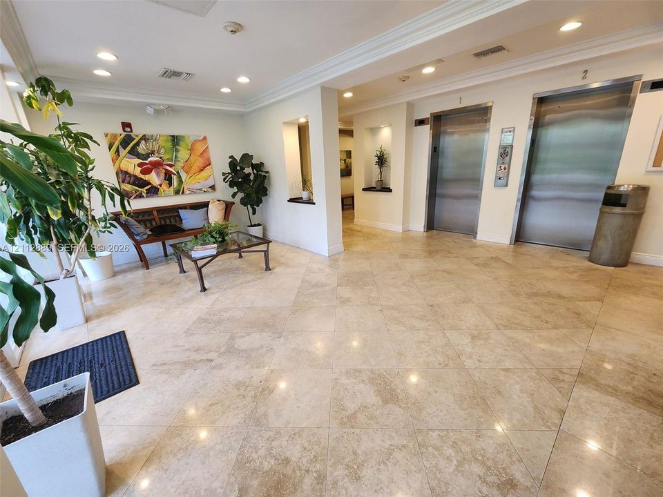 Lobby featuring polished stone tile flooring, stainless steel elevator doors, recessed ceiling lighting, and built-in wall niches