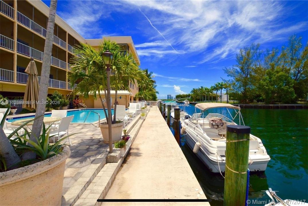 Waterfront property featuring a concrete boat dock, a swimming pool with paved decking, and structural balconies