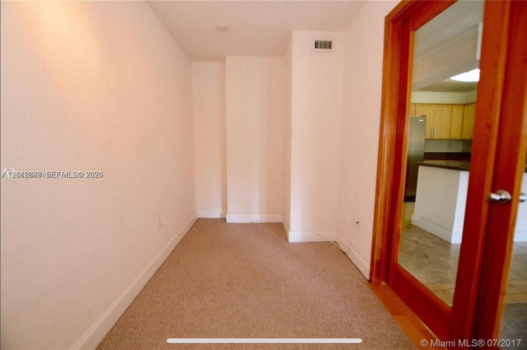 Enclosed space featuring neutral carpeting and a natural wood-finish door frame with a full-length glass panel