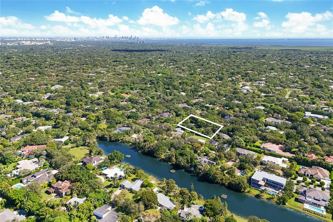 Aerial perspective showcasing a parcel of land defined by mature trees and natural greenery within an established residential area