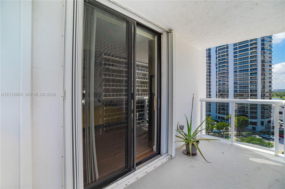 Covered balcony featuring a white metal railing and sliding glass door entrance