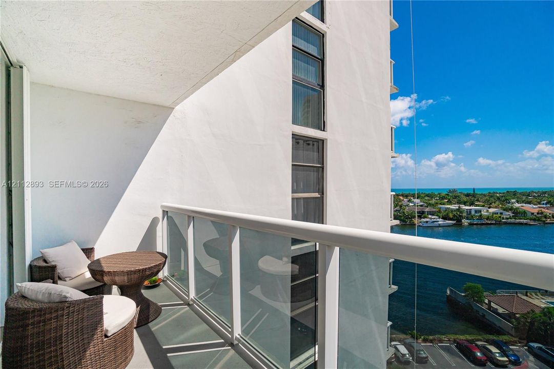 Covered balcony featuring a glass and aluminum railing, concrete flooring, and water frontage