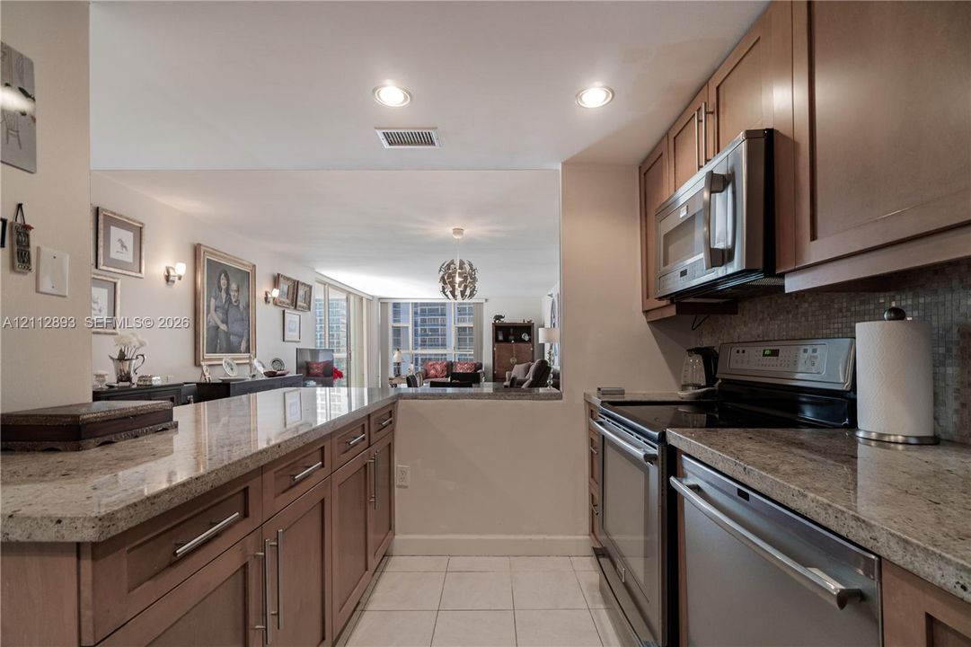 Kitchen featuring stone countertops, natural wood-finish cabinetry, stainless steel appliances, and recessed lighting