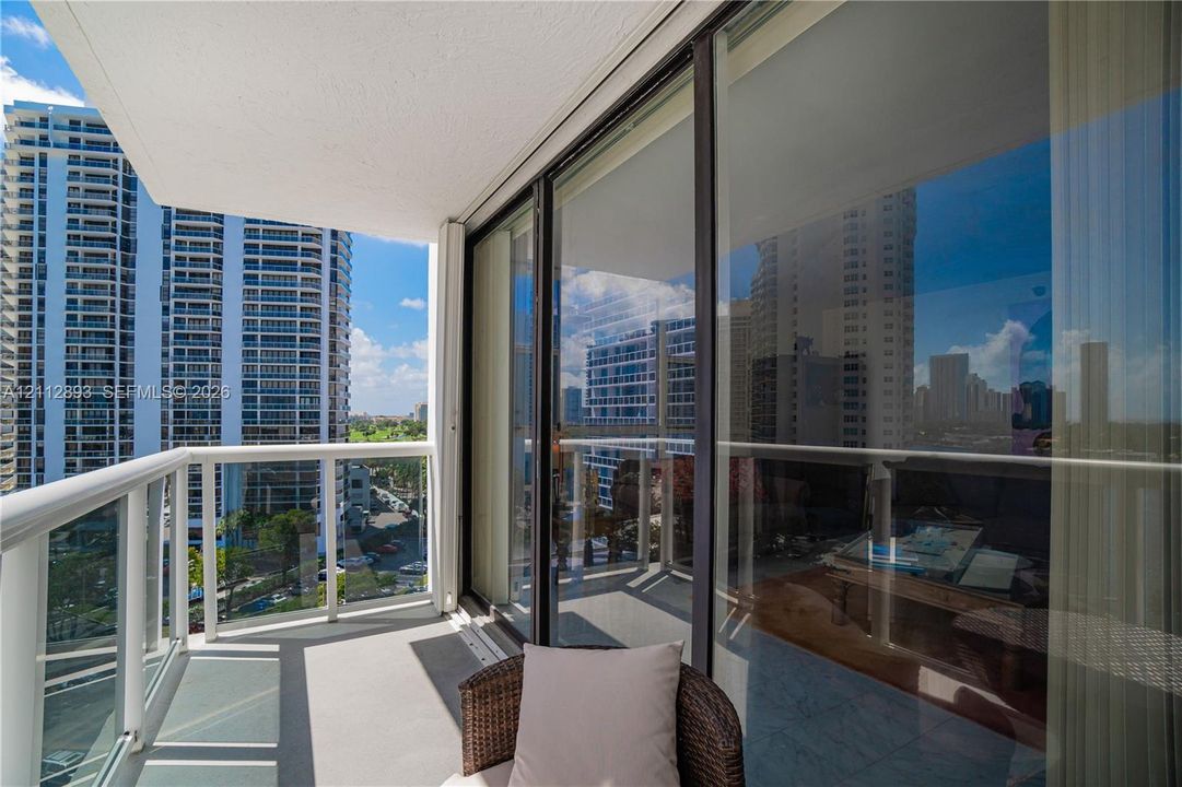 Private balcony featuring a glass-panel railing, smooth concrete flooring, and full-height sliding glass doors