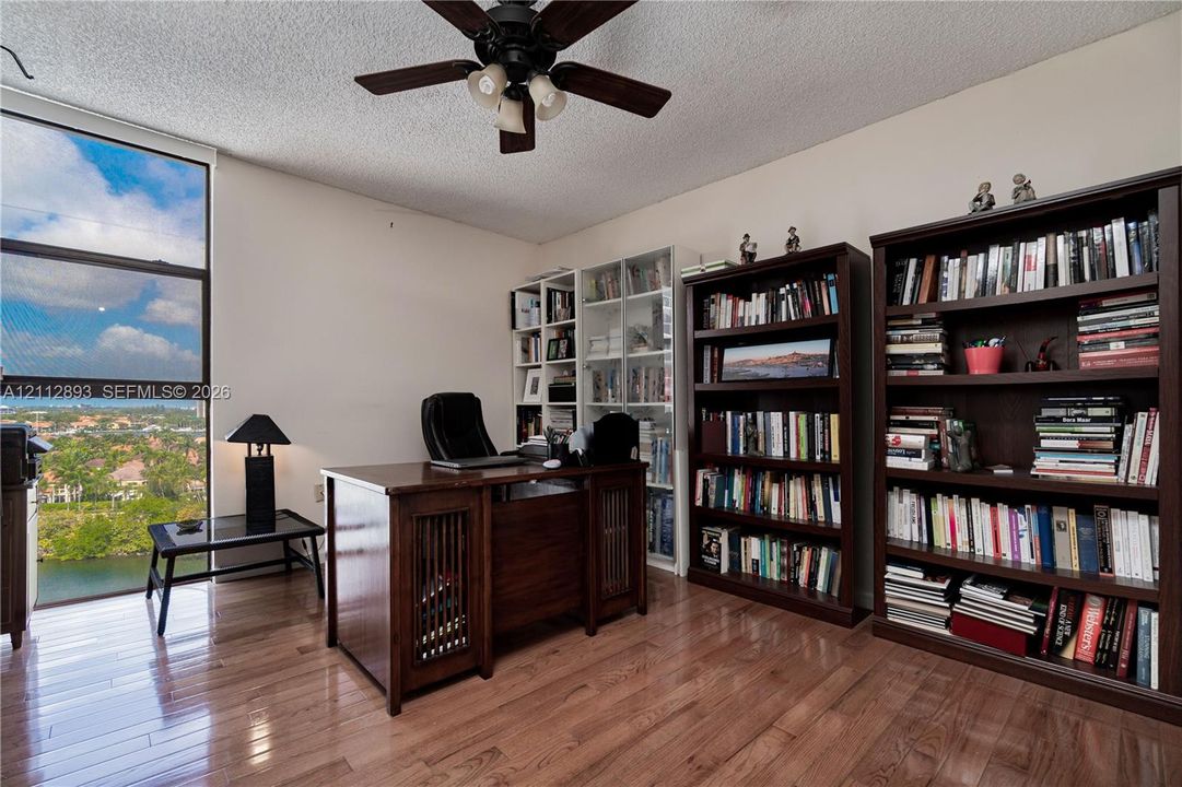 Floor-to-ceiling window featuring natural light, wood-finish flooring, and an attached ceiling fan with lighting
