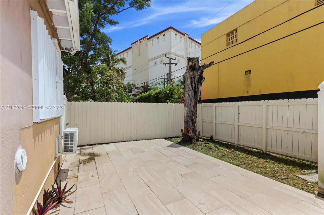 Paved outdoor patio space enclosed by white vertical-panel fencing
