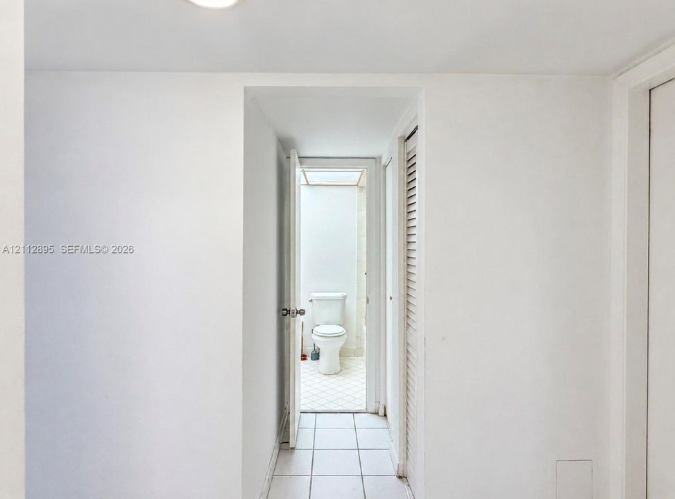 Ceramic tile flooring, louvered bi-fold doors, and a porcelain toilet fixture