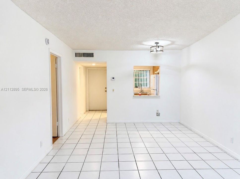 Interior space featuring large-format square tile flooring, a pass-through window to the kitchen, and a circular drum-style ceiling light fixture