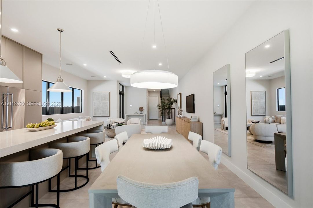 Open-concept interior featuring a kitchen island with stone countertop, large-scale drum pendant lighting, flush-mount recessed ceiling lights, and wall-to-wall mirrors