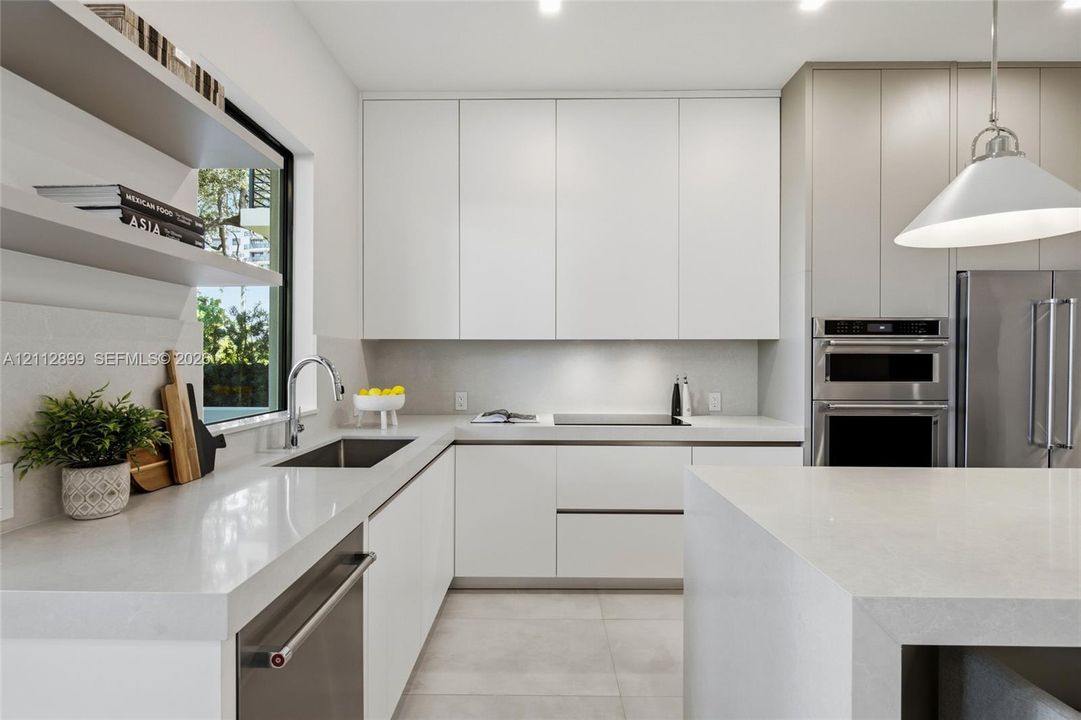 Modern kitchen featuring flat-panel cabinetry, light-toned stone countertops, built-in stainless steel appliances, dual open floating shelves, and an oversized island