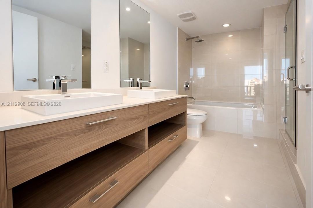 Floating double vanity with wood-finish cabinetry, white rectangular vessel sinks, quartz countertops, and a tiled shower-tub combination with a glass enclosure