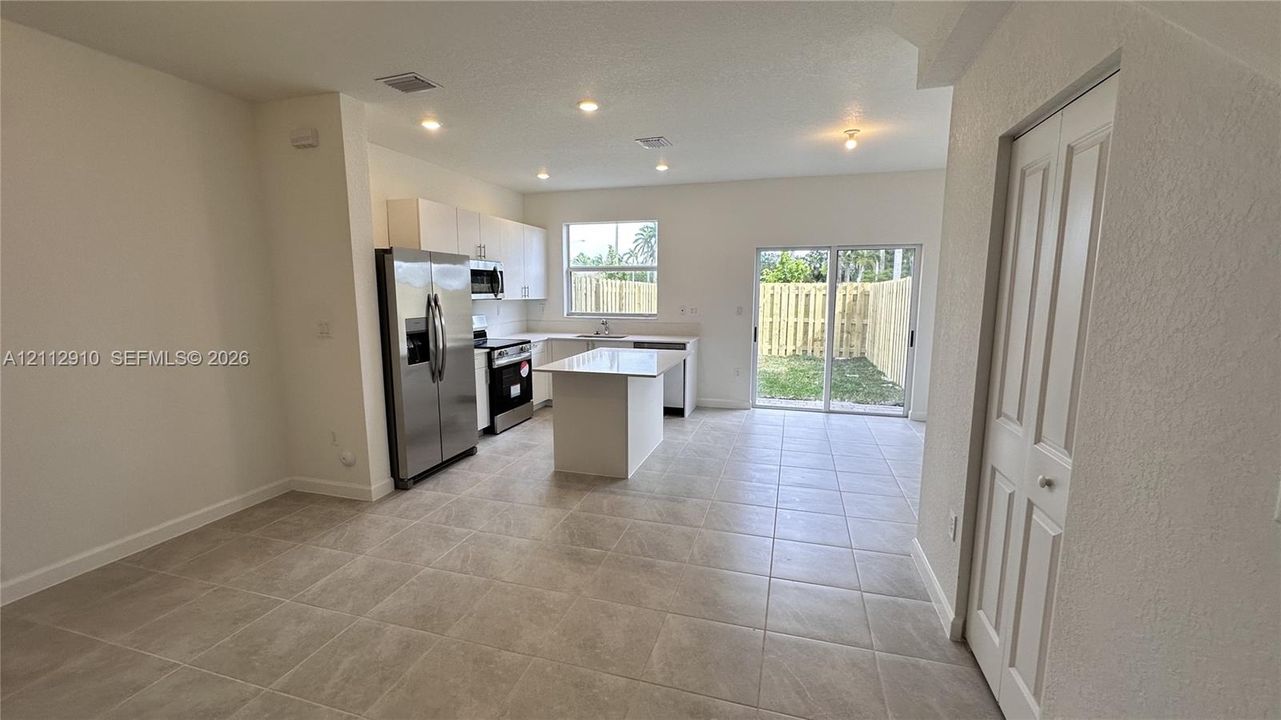 Kitchen featuring white cabinetry, center island, stainless steel refrigerator, recessed lighting, and tile flooring throughout