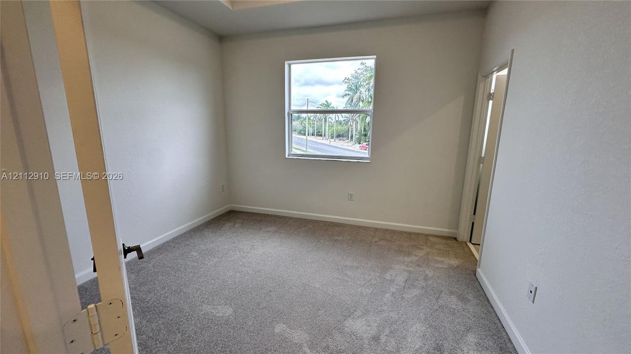 Neutral-toned interior room featuring carpeted flooring, a recessed ceiling detail, and a single-pane window
