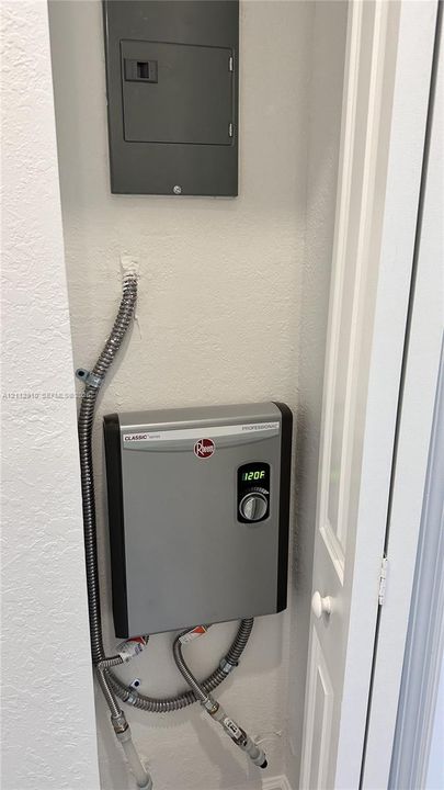 Wall-mounted electric tankless water heater featuring a digital temperature display and integrated circuit breaker panel