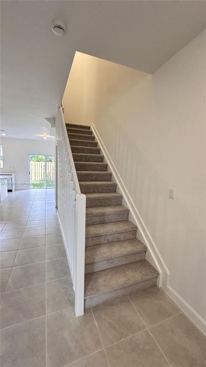 Staircase featuring carpeted treads and a white painted spindle railing