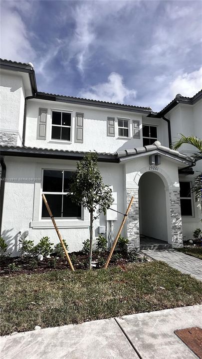Stucco exterior featuring stacked stone accents, arched entryway, and neutral-toned window shutters